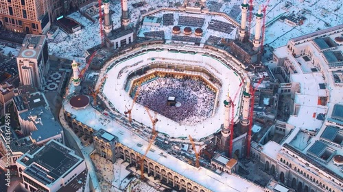 Aerial view showing crowds of pilgrims gathered around the Kaaba in the Grand Mosque, with construction cranes surrounding the site in Mecca