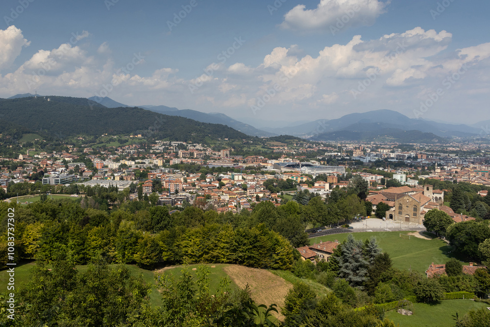Naklejka premium Aerial summer view of the new city of Bergamo (Citta Bassa) from the city walls of the old town (Citta Alta), in Lombardy, Italy. Copy space above.