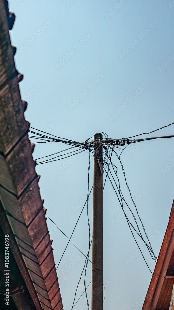 Fototapeta premium Photo of a towering electricity pole with wires stretching in all directions in a place with a beautiful photo angle