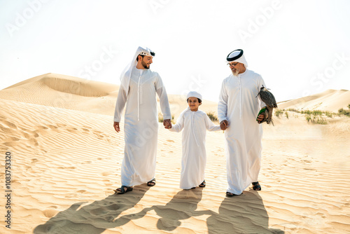 Three generation family making a safari in the desert of Dubai. Grandfather, son and grandson spending time together in the nature and training their falcon bird. photo