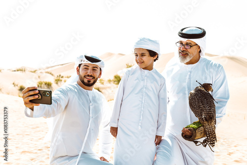 Three generation family making a safari in the desert of Dubai. Grandfather, son and grandson spending time together in the nature and training their falcon bird. photo