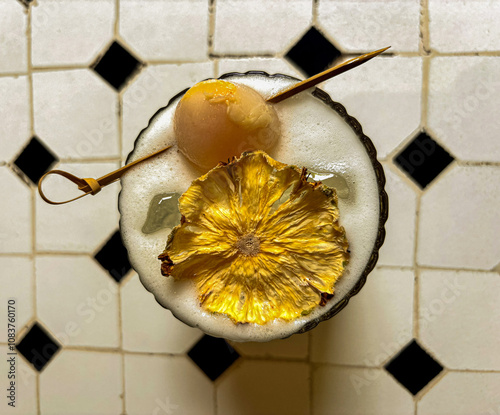 a glass of pineapple lemon squash drink topped with lychee and dried pineapple pieces.