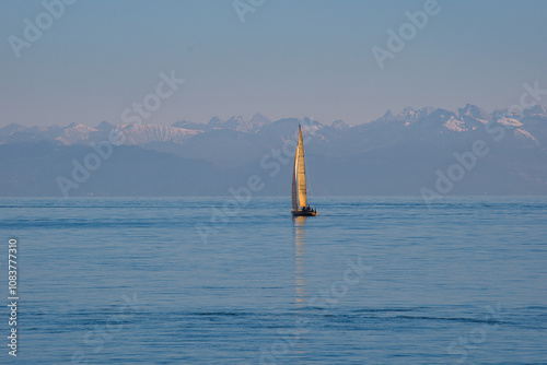 Segelboot auf dem Bodensee im Herbst vor den schneebedeckten Alpen photo