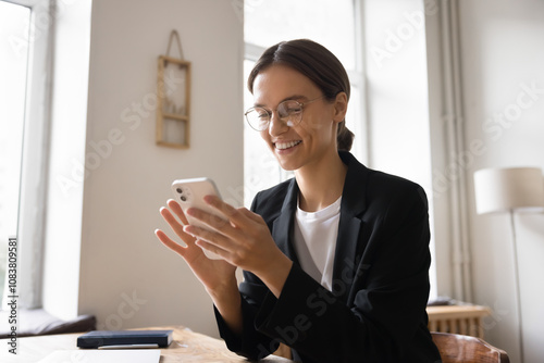 Young businesswoman engaged in professional or business-related tasks using her smartphone, smile, reading e-mail or message, planning or organizing her workday, managing meetings through mobile app