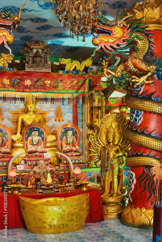  Interior of a richly decorated Thai-Chinese Buddhist temple. Golden statues, colorful dragon. Temple Wat Maneewong, Nakhon Nayok photo