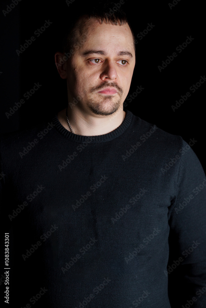 Obraz premium Introspective Man in a Black Sweater Against a Dark Background