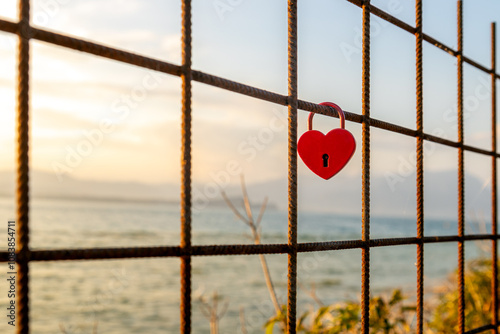 A red love lock attached to the fence overlooking Lake Garda in Sirmione, Italy