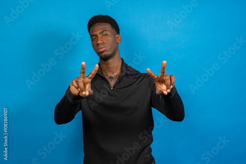 Young man showing peace sign with both hands on blue background