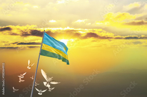 Rwanda flag waving with flying doves against sunset or sunrise. Rwanda flag for Republic Day and Independence Day. photo