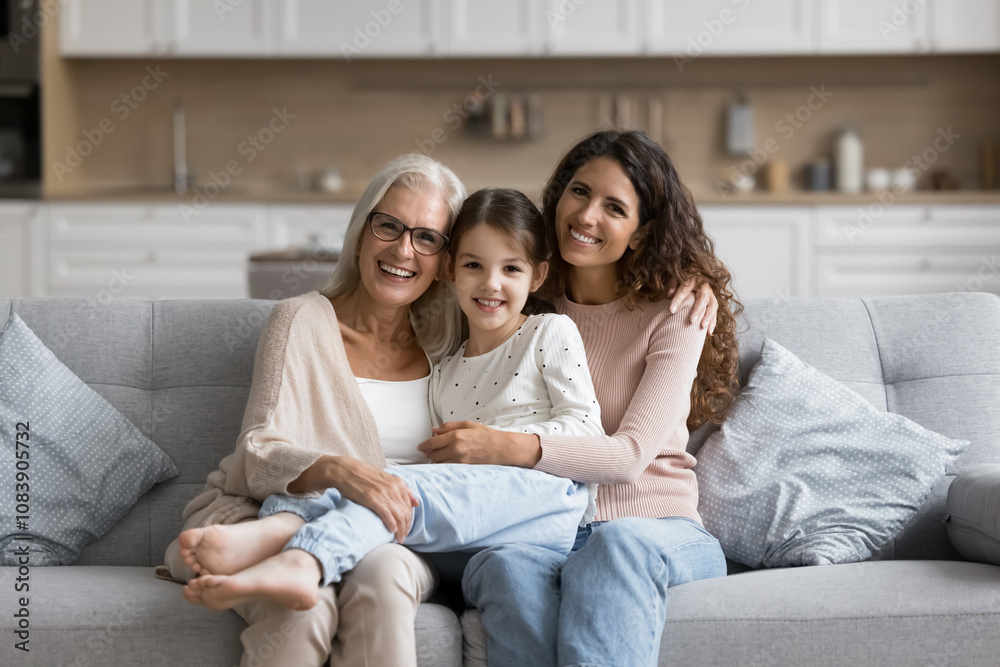 © fizkes - Portrait of pretty three generational family women posing for camera resting together on cozy couch. Lovely little girl enjoying priceless time with older granny and young mommy at home. Ties, love © fizkes - Portrait of pretty three generational family women posing for camera resting together on cozy couch. Lovely little girl enjoying priceless time with older granny and young mommy at home. Ties, love