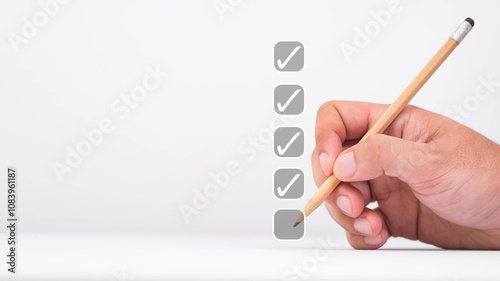 A hand holding a pencil checks off an item on a list, symbolizing tasks completed in a minimalistic, clean composition. photo