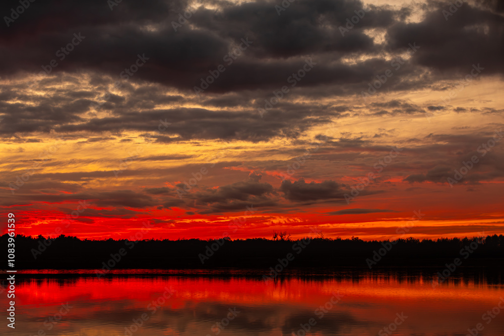 Fototapeta premium A Stunning Sunset Over Serene Lake With Beautiful Reflections in the Calm Waters