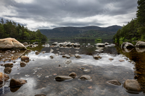 The stones protruding above the water in the lake of Loch an Eilein, in the northwest of Scotland in the Rothiemurchus forest, Cairngorms National Park, Scotland photo