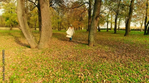 Slow motion of young blond hair female woman running in the forest  Sunny autumn day