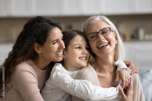 Картината върху платно Three generational women embracing, smiling spending pleasant time together, celebrate life event, Happy Mother Day at home, close up