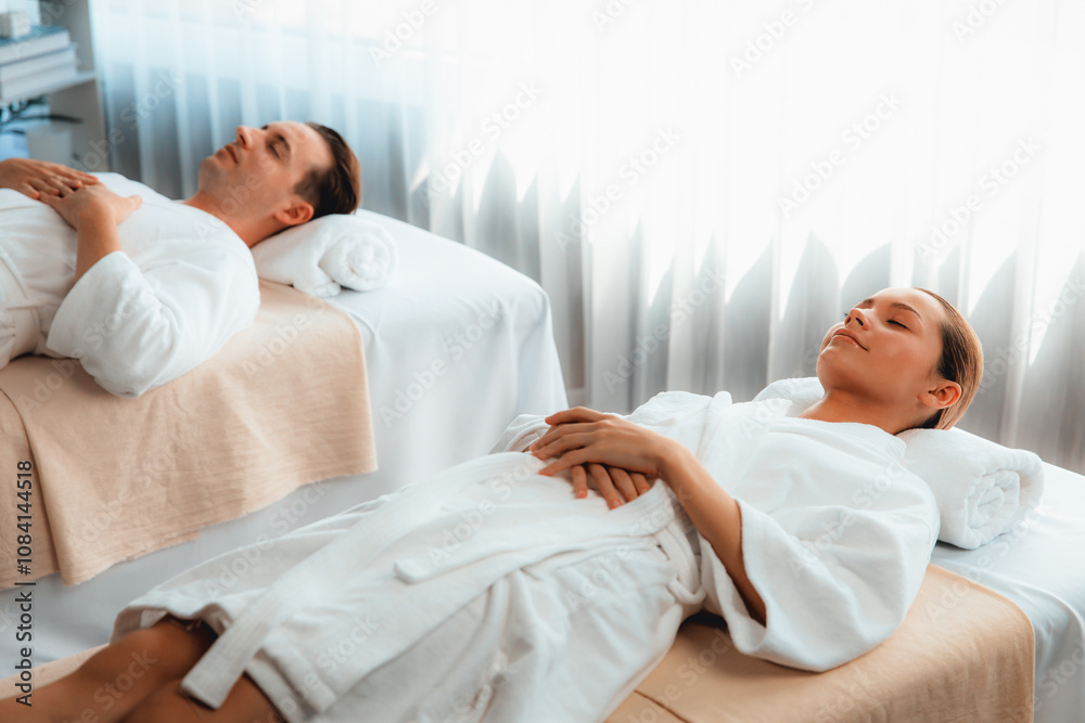 Obraz premium Caucasian couple customer enjoying relaxing anti-stress spa massage and pampering with beauty skin recreation leisure in day light ambient salon spa at luxury resort or hotel. Quiescent