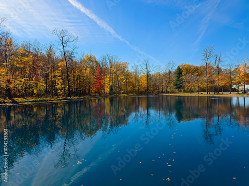 Fall colors glow across a pond in a northeast Ohio city park on a late autumn summer morning.