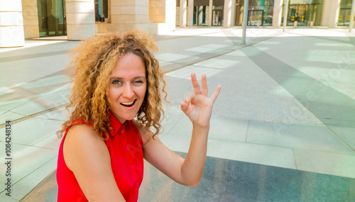 Beautiful fashionable businesswoman smiling making and showing ok hand sign fingers winking with one eye