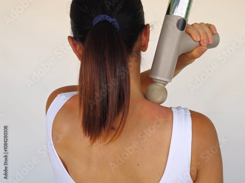 Young woman with percussive massager on white background, back view concept photo