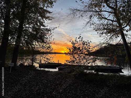 Serene Lakeside Sunset With Boats and Autumn Trees