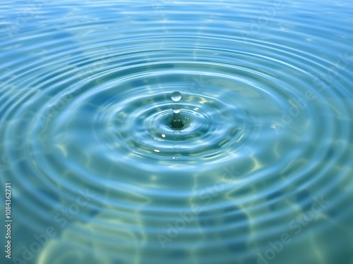 A calm clear water surface with a single drop creating circular waves that radiate outward in all directions, wave patterns, natural beauty, circular waves