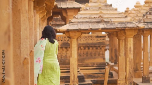 Indian woman wearing traditional salwar kameez exploring beautiful architecture of Bada Bagh in Jaisalmer, Rajasthan, India. Tourist girl enjoying holidays during her culture trip to India. Travel bac photo