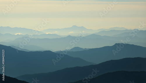 Layered Mountain Ranges: A majestic panorama of mountain ranges, bathed in the ethereal glow of a soft light, unfolds before your eyes. The layers of mountains.