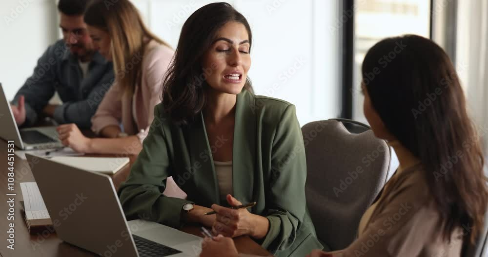 Positive confident beautiful Latin businesswoman talking to female office colleague at workplace in co-working office, explaining task to new employee, intern, speaking to coworker Positive confident beautiful Latin businesswoman talking to female office colleague at workplace in co-working office, explaining task to new employee, intern, speaking to coworker