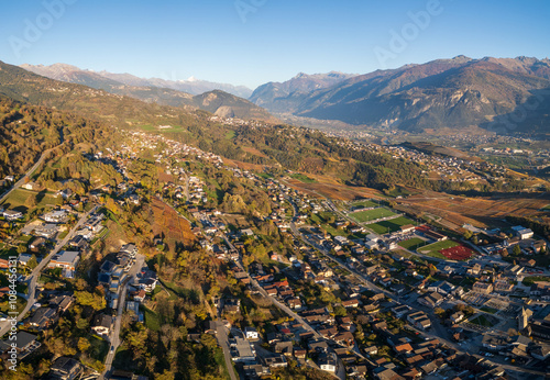 Autumn aerial drone view in evening light across the towns of Savièse and Sion in the Rhone Valley of the canton of Valais in Switzerland, overlooking the Pennine Alps