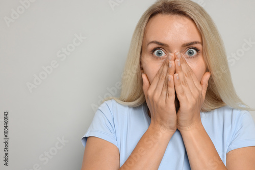 Portrait of scared woman on gray background, space for text