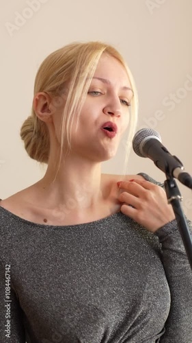 joyful beautiful Caucasian young woman singing to microphone, record of new musical reals, female singer