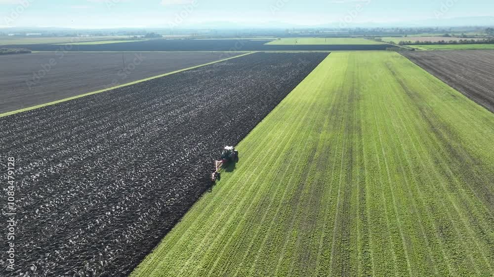 Vue d'avion d'un tracteur en train de labourer un champ immense pour illustrer le monde agricole et l'agriculture en France