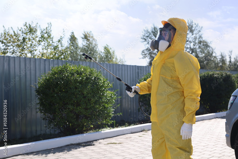 Pest control worker with spray tank outdoors Pest control worker with spray tank outdoors