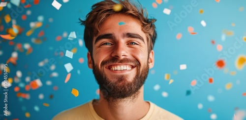 Happy man smiling in vibrant setting with colorful confetti during celebratio...