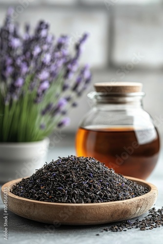 Glass jar of herbal tea next to dried lavender and fresh flowers on a wooden ...