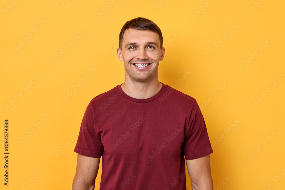 Obraz premium Smiling man with dental braces on yellow background