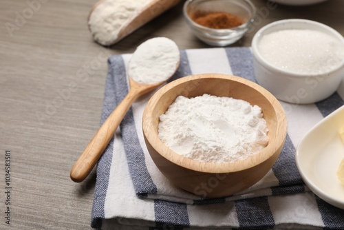 Baking powder in bowl and sugar on wooden table, closeup