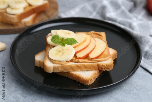 Tasty sandwich with peanut butter, apple, banana and mint on grey table, closeup