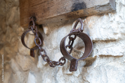 Old medieval patinaed handcuffs on the stone wall photo