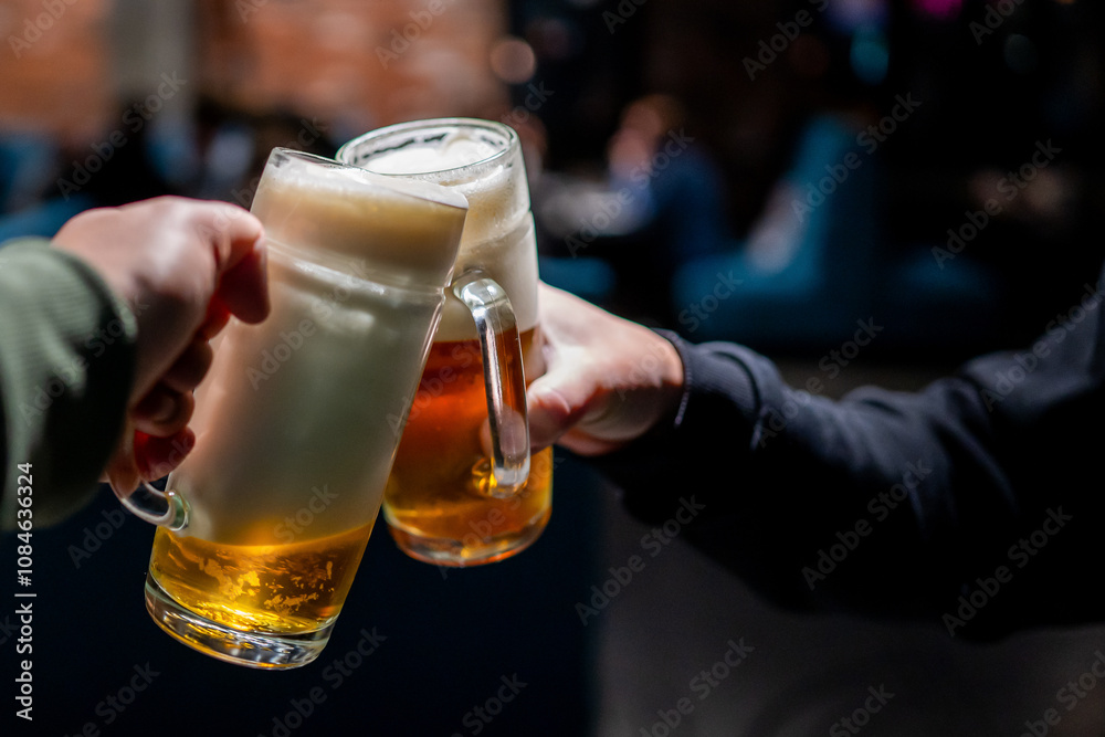 Φωτογραφία Two hands holding beer mugs in a celebratory toast against a blurred background