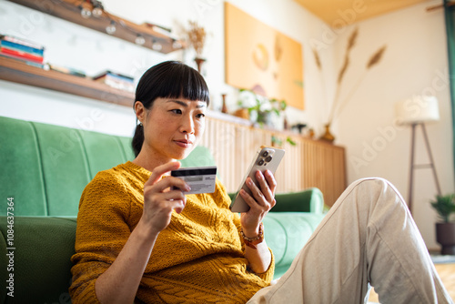 Woman making online payment with credit card and smartphone at home