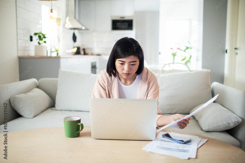 Asian woman working on laptop from home couch Asian woman working on laptop from home couch