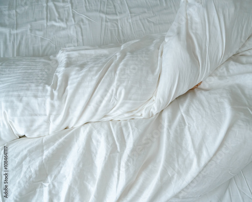 The feet of a small child in a parent's bed on white sheets rolled in a white blanket 