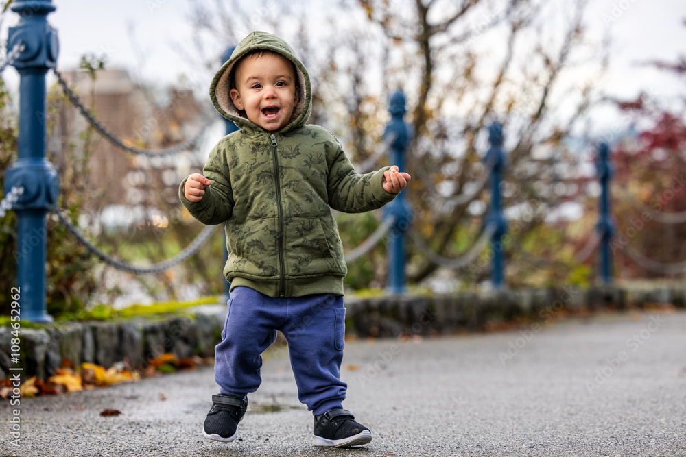 Fototapeta premium Joyful Toddler Walking in Park on a Cloudy Day