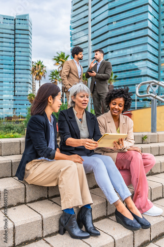 Businesswomen sitting in outdoor urban stairs working with digital tablet