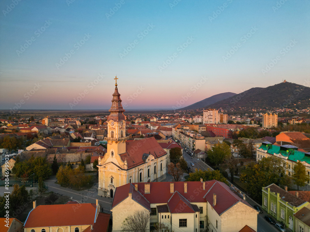 Obraz premium European bell tower with old red roof town in the background, Vršac, Serbia - aerial drone photo