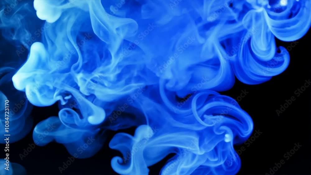 Ethereal blue smoke swirling in fluid movement against dark background creates captivating and mysterious abstract visual experience.