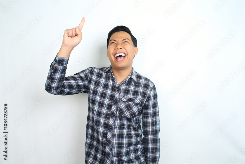 carefree asian man pointing hand with laughing expression showing joy and playful emotion wearing casual plaid shirt isolated on white background carefree asian man pointing hand with laughing expression showing joy and playful emotion wearing casual plaid shirt isolated on white background