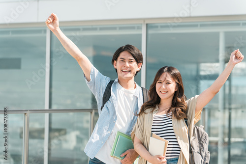 Foto キャンパス・オフィスビルの前でガッツポーズをする男女の大学生・若いビジネスマン