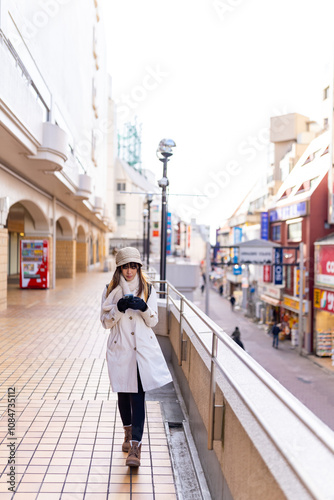 Asian woman using navigation online map on smartphone with internet during walking on city street in Tokyo, Japan. Attractive girl enjoy outdoor lifestyle travel in the city on winter holiday vacation